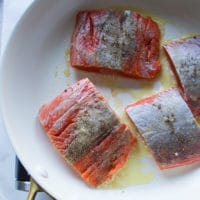 Sockeye salmon seasoned and placed in the buttered skillet to sear