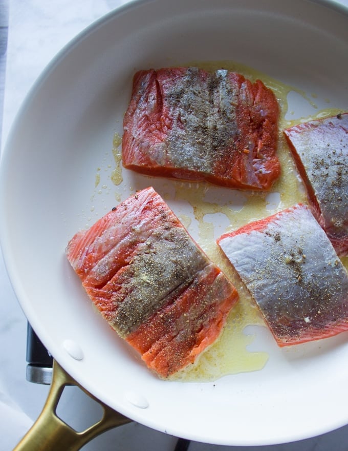 Sockeye salmon seasoned and placed in the buttered skillet to sear