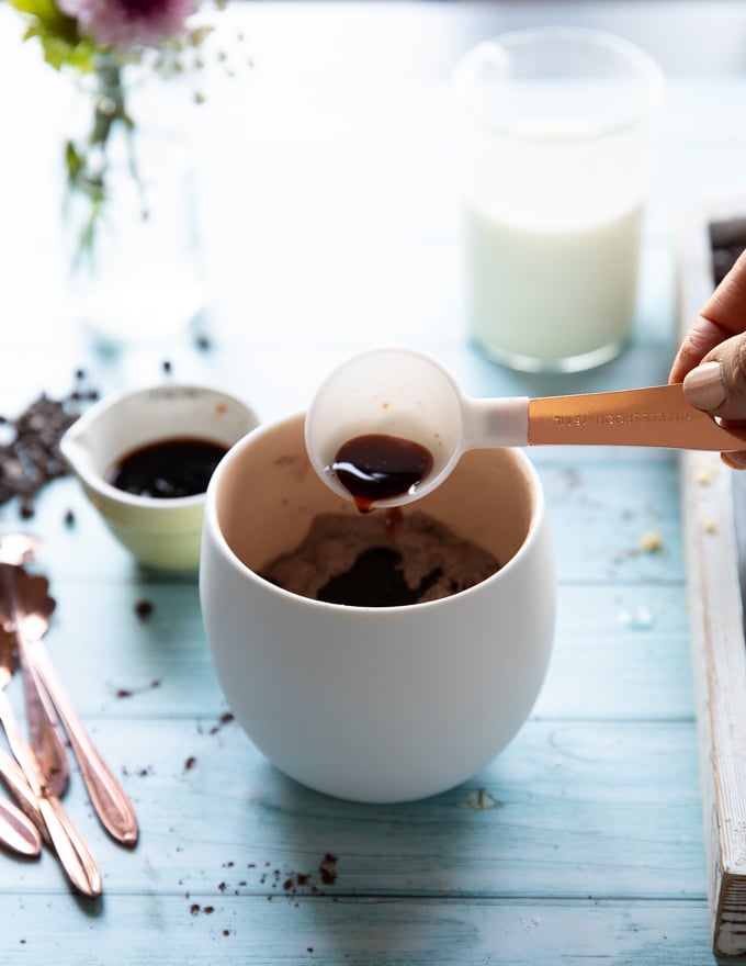 A hand adding the vanilla to the mug