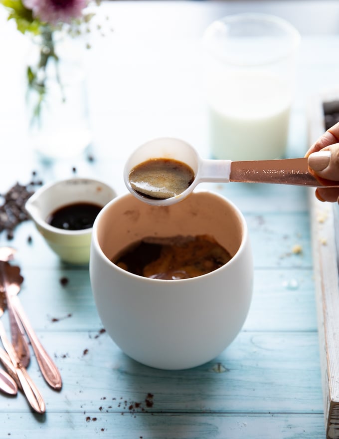 A tablespoon of coffee being added to the mug to make coffee brownie in a mug (optional)