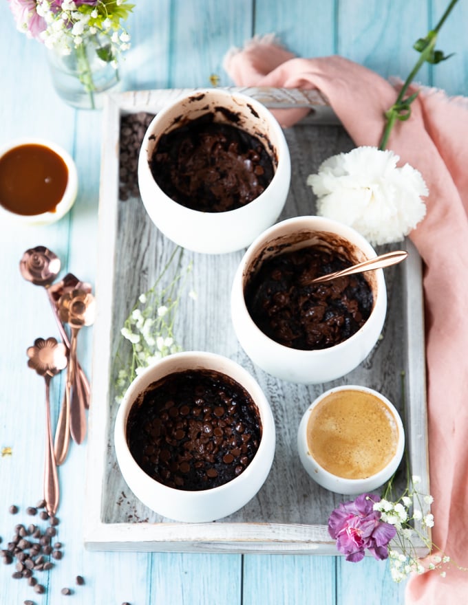 three mugs with brownies cooked in them on a tray with a cup of espresso on the side