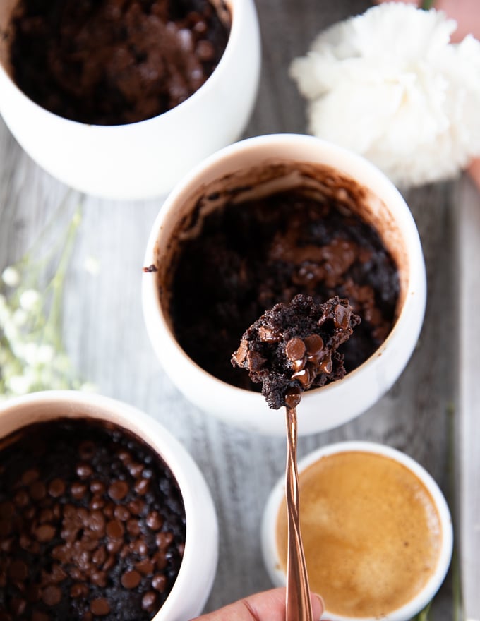 A spoon scooping out some brownies from the brownie in a mug