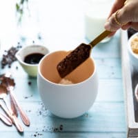 A spoon adding i the cocoa powder to the mug