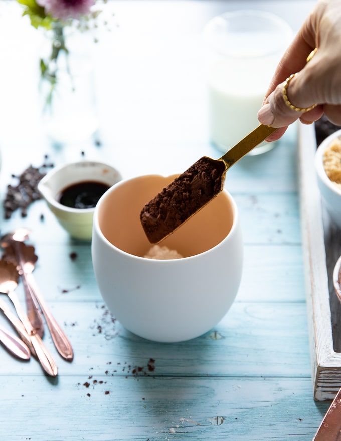 A spoon adding i the cocoa powder to the mug