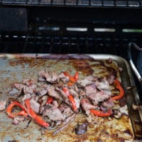 Meat and veggies mixture on a griddle cooking