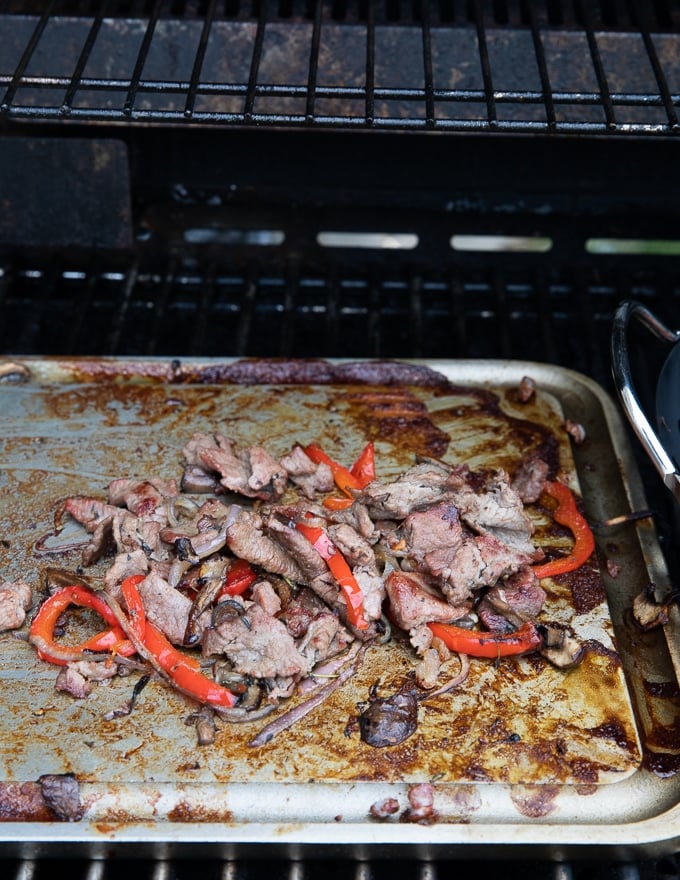 Meat and veggies mixture on a griddle cooking