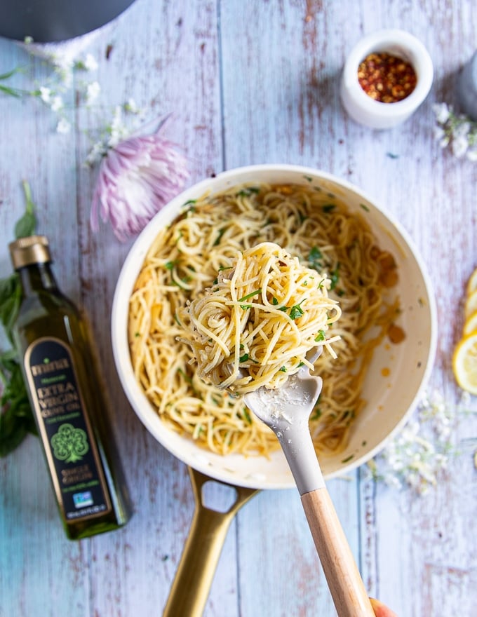 cooked spaghetti being added to the olive oil skillet once the garlic and olive oil sauce is ready