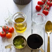 ingredients to make the caprese salad dressing including basil pesto, balsamic vinegar and olive oil