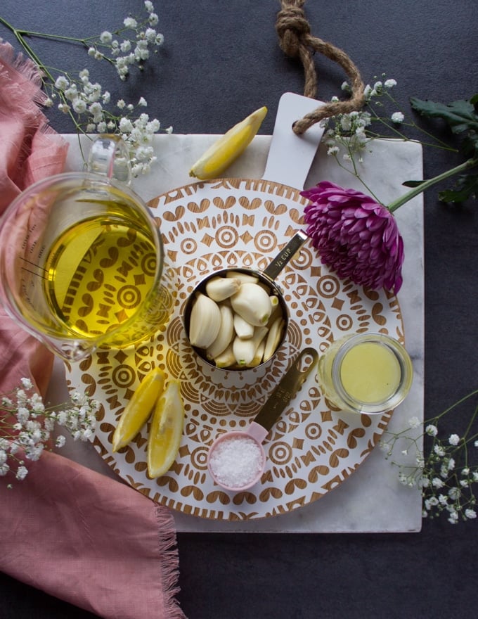 ingredients to make creamy garlic sauce on a white board including garlic, oil, lemon juice and salt to make the toum sauce