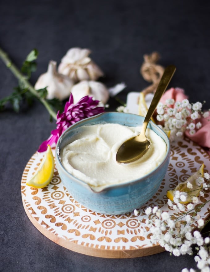 A spoon sliding over a bow of garlic sauce recipe showing the thickness of the sauce