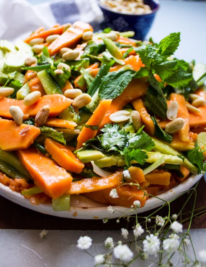 close up of the papaya salad on a plate showing the shredded papaya, cucumebrs, mint and cashews close up