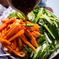 A hand drizzling the papaya salad dressing over the papaya salad recipe