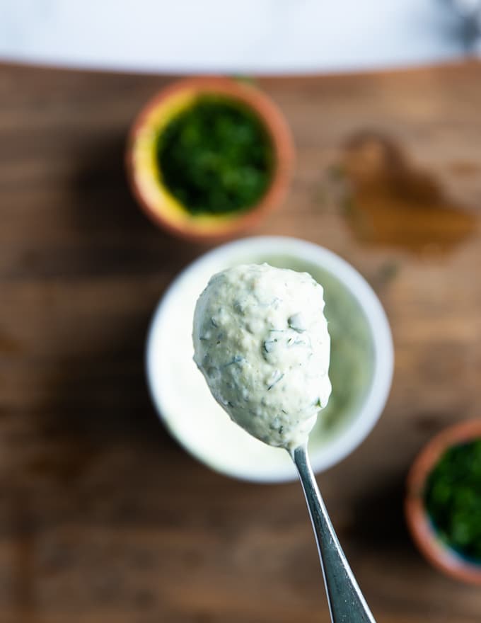 A spoon holding off tartar sauce close up showing the creamy texture of the sauce