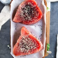 seasoned tuna steaks with sesame seeds and salt on a parchment paper ready to sear