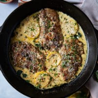 The finished veal scallopini in piccata sauce is ready and garnished with herbs and lemon slices