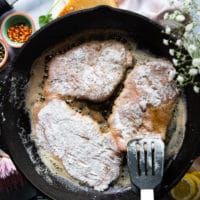 The veal scallopini placed in a large cast iron pan with melted butter