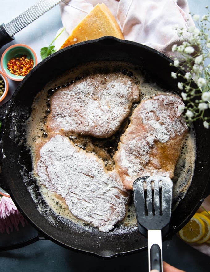 The veal scallopini placed in a large cast iron pan with melted butter 