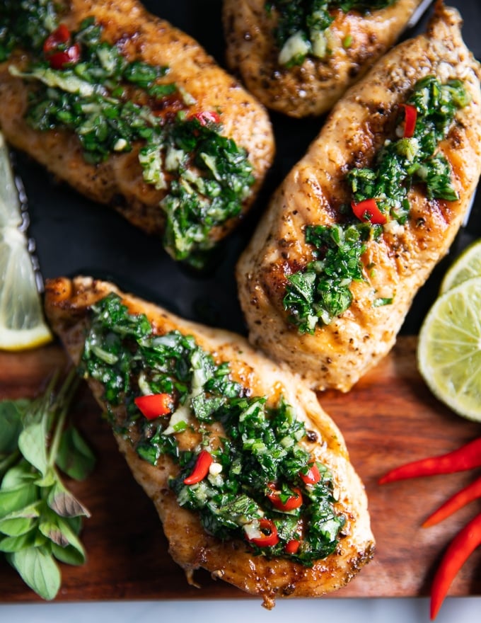 close up of three pieces of chicken chimichurri drenched with chimichurri sauce