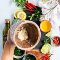 A hand holding a mortar and pestle showing how finely minced the garlic is to make chimichurri sauce