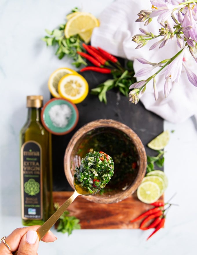 A spoon holding off some chimichurri sauce showing off the final texture and sauce