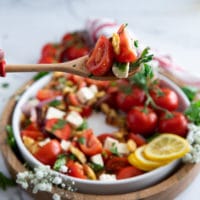 A salad serving spoon serving up some tomato salad showing how juicy the tomatoes are