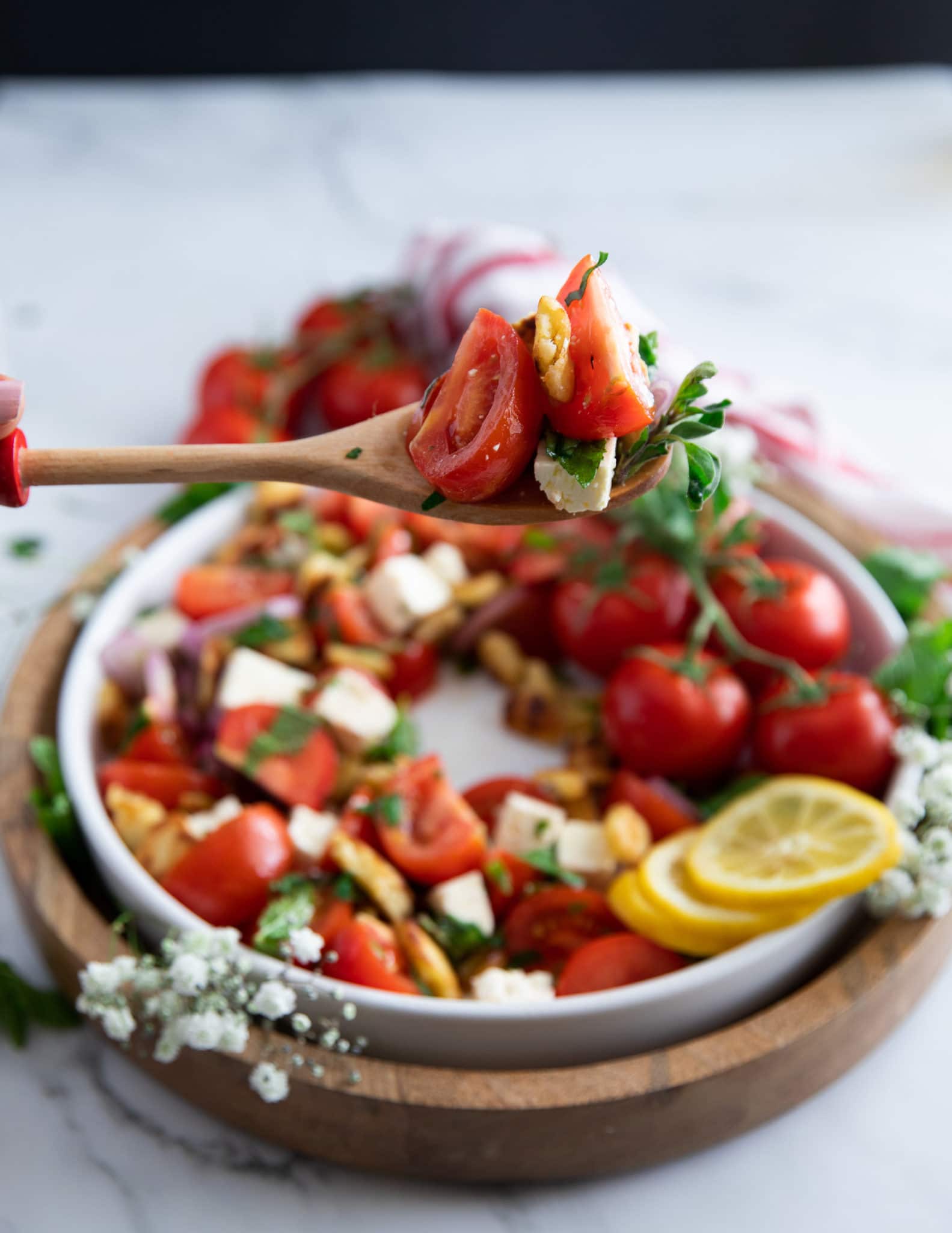 A salad serving spoon serving up some tomato salad showing how juicy the tomatoes are