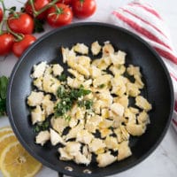 torn up pita chunks in a skillet and osme oregano on top, and fresh garlic and olive oil , ready to be tossed