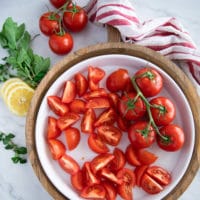 A large salad plate with fresh tomatoes quartered ready to assemble the tomato salad recipe