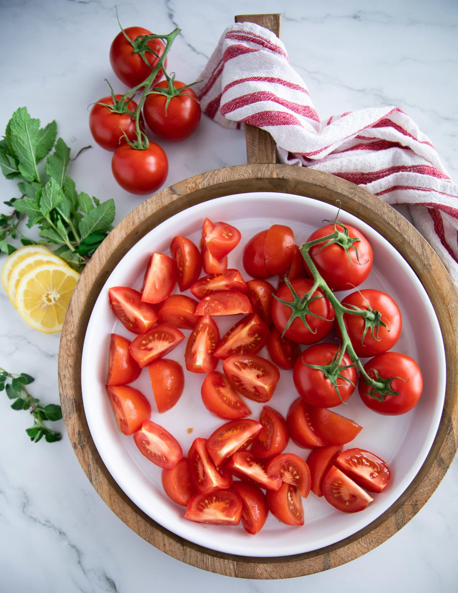 A large salad plate with fresh tomatoes quartered ready to assemble the tomato salad recipe