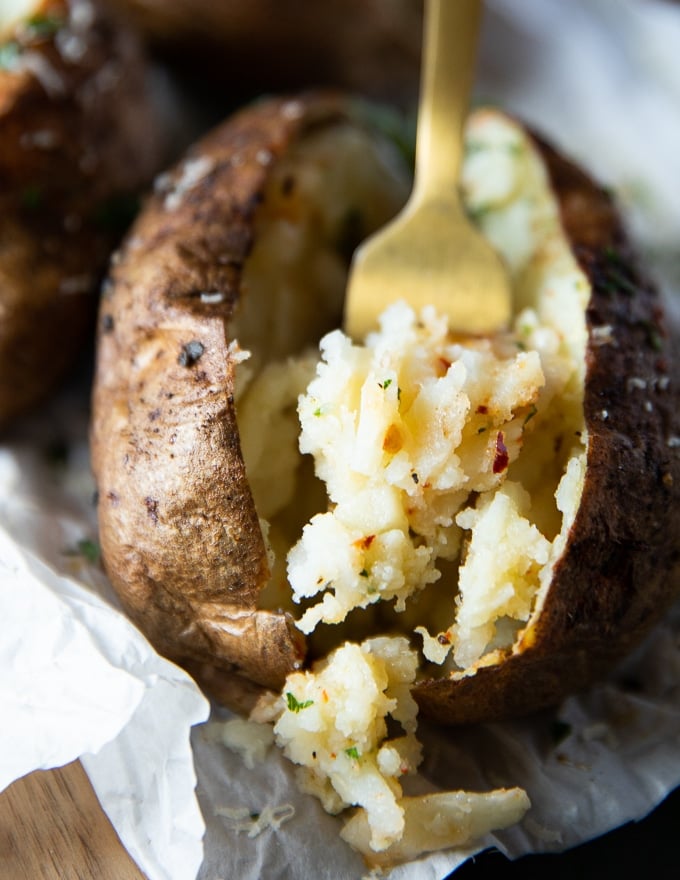 A fork showing the inside of an air fryer baked potato showing the fluffy inside