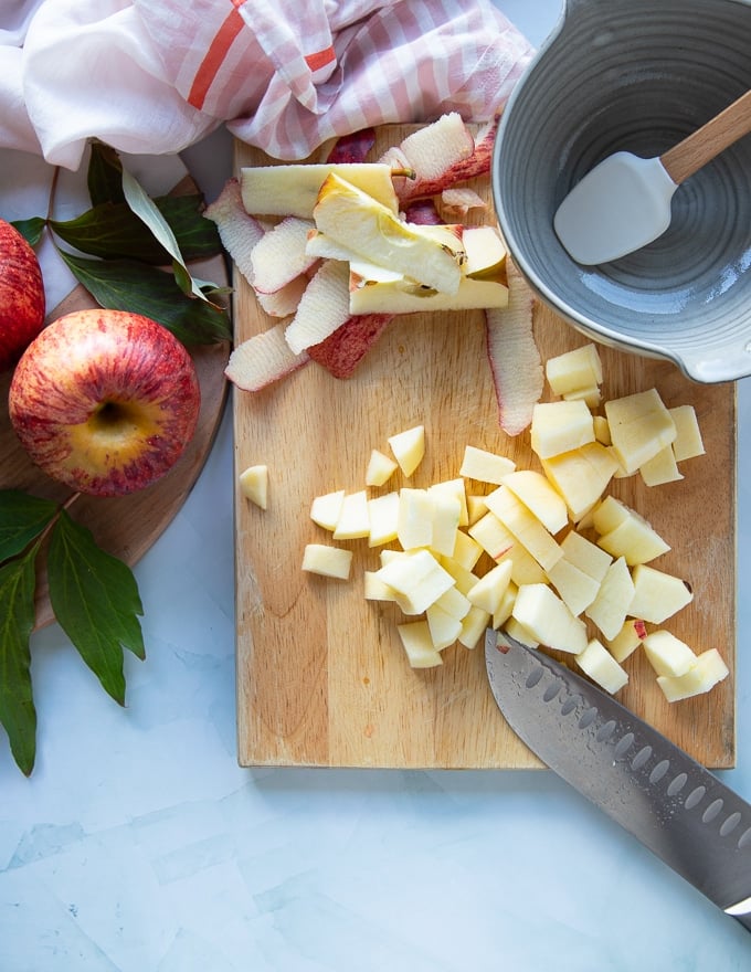 Apples being chopped on a cutting board, peeled and desseded
