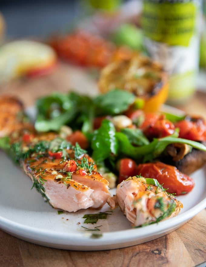 A piece of flaked grilled salmon on a plate showing how juicy and succulent the grilled salmon recipe is