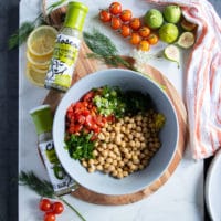 chickpea salad ingredients to serve with the grilled salmon recipe including a bowl of chickpeas, fresh herbs, tomatoes and green onions