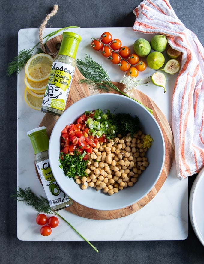 chickpea salad ingredients to serve with the grilled salmon recipe including a bowl of chickpeas, fresh herbs, tomatoes and green onions