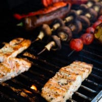 flipped salmon over the bbq grill showing the texture and chars o the salmon, also grilled veggies on the BBQ next to the salmon