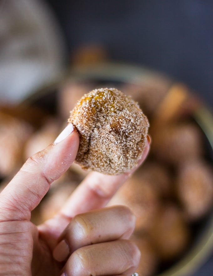 One hand holding a donut hole showing the shape of it