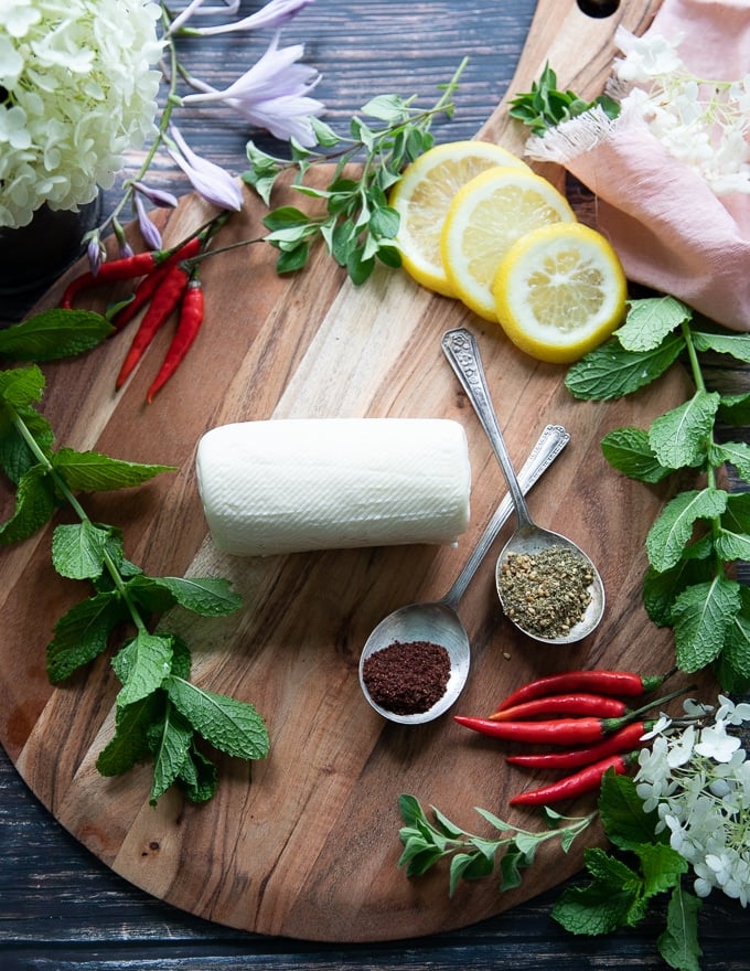 a block of halloumi cheese on a wooden board surrounded by lemon slices and mint