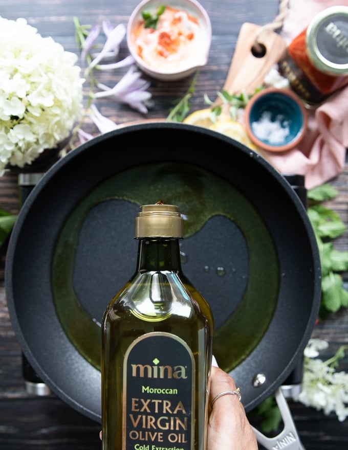 Olive oil being poured in a skillet for frying the halloumi cheese