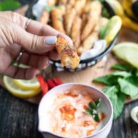 A hand holding a halloumi fries bitten to show the texture of the fried cheese and the sauce