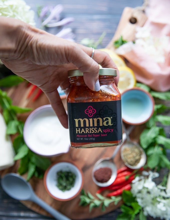 A hand holding a jar of harissa