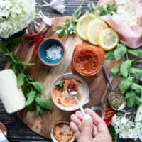 A hand mixing the yogurt harissa sauce in a bowl