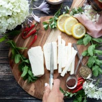 A hand slicing the block of halloumi cheese into strips the thickness and size of french fries