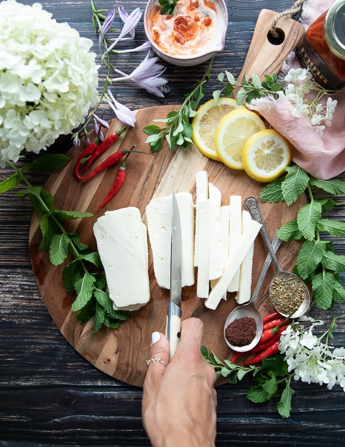 A hand slicing the block of halloumi cheese into strips the thickness and size of french fries