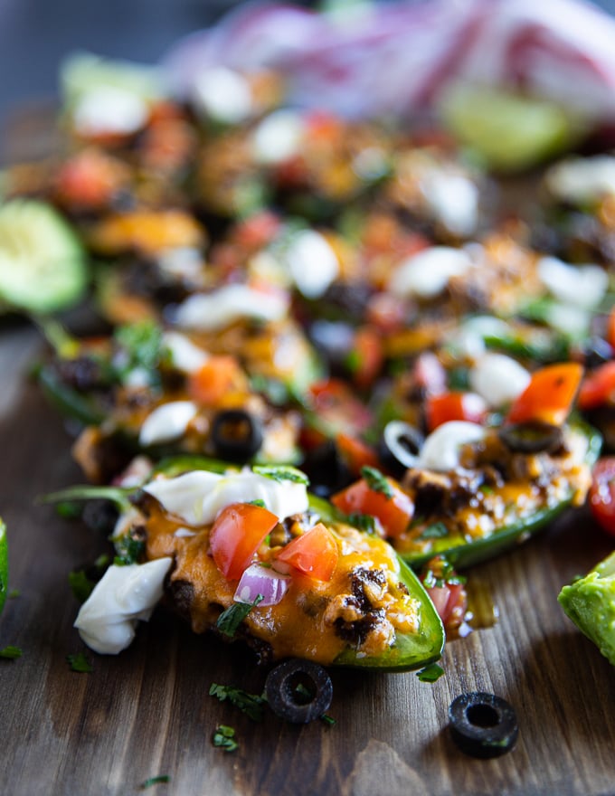 one baked jalapeno popper on a cutting board toped with cheese