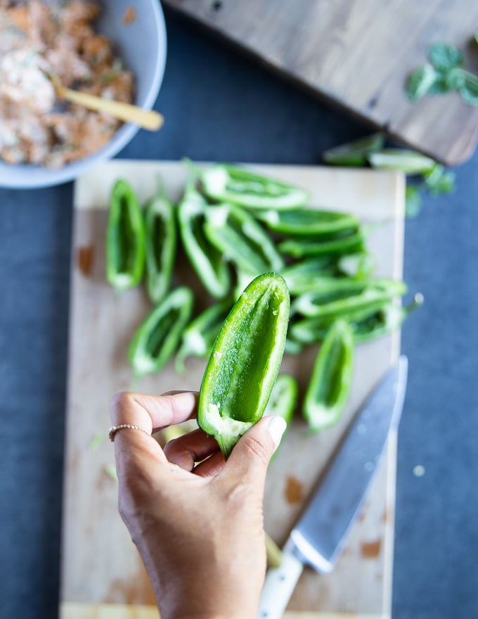 A handholding a jalapeño pepper cut in half, deseeded to remove the spice from it