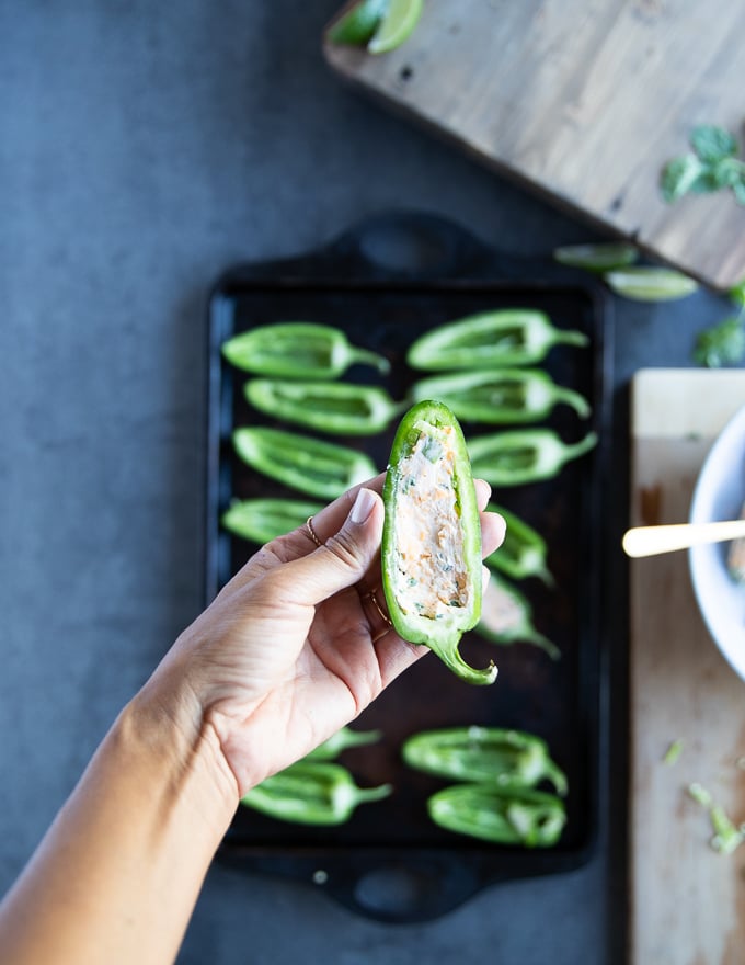 A hand holding a jalapeño pepper stuffed with the cheese mixture