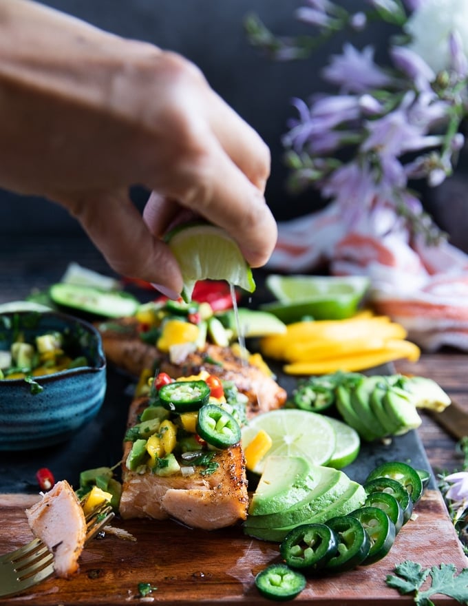 A hand squeezing a lime over air fryer salmon