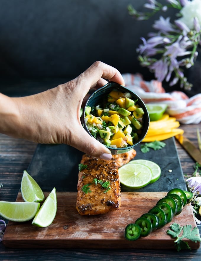 A hand holding a bowl of avocado salmon salsa to serve with the air fryer salmon