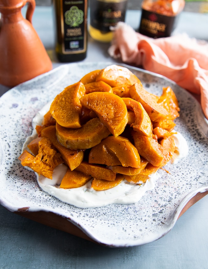 The roasted honeynut squash is added over the yogurt sauce