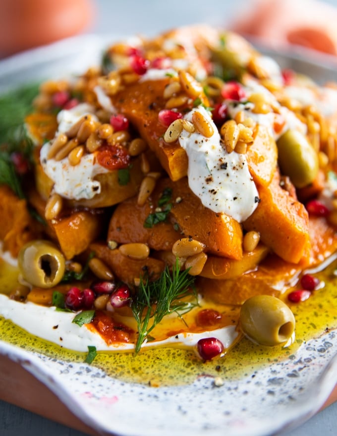 close up of the honeynut squash and dollops of yogurt, dill, olive oil, harissa, pine nuts and pomegranate arils